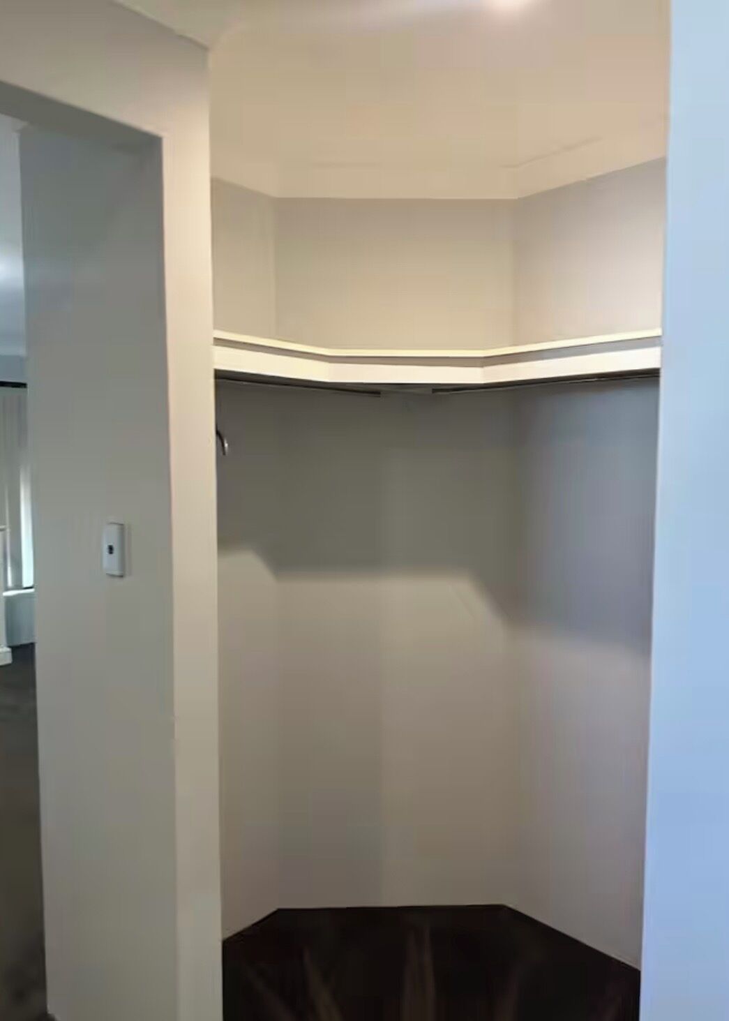 Een kamer met een inbouwkast, een deur en een lichtschakelaar op de muur.