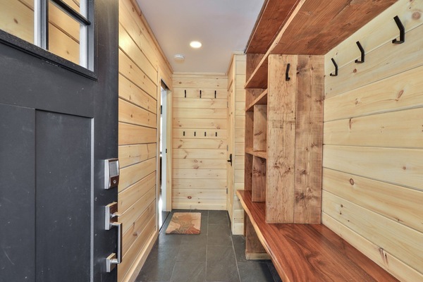 Long benches, hooks, and open shelves organize coats and gear near the door.