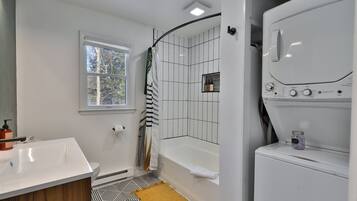 A modern bathroom with a white sink, a bathtub, and a shower area.