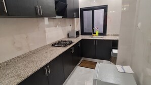 Una cocina moderna con armarios oscuros, encimera de granito, estufa a gas y un lavabo con ventana arriba.