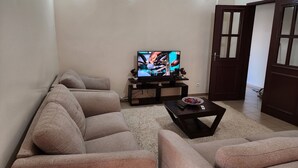 Una sala de estar con un conjunto de sofá, una mesa de centro y un televisor sobre un mueble.