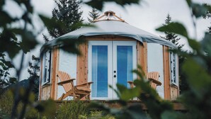 Una yurta de madera con dos puertas y dos sillas afuera.