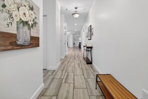 A hallway with a wooden bench, a vase with flowers, and a ceiling light. - 4715 SH - Storey Lake Hideaway 6BR Mansion Private Pool (Kissimmee)
