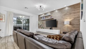 Un salon moderne avec un canapé en cuir, un téléviseur à écran plat et un mur décoratif en bois.