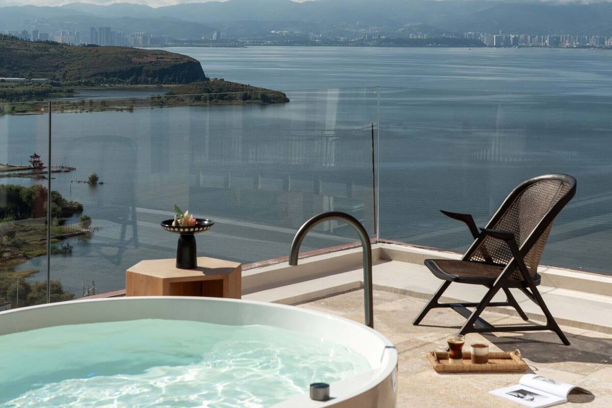 A hot tub with a clear view of a body of water and distant cityscape.