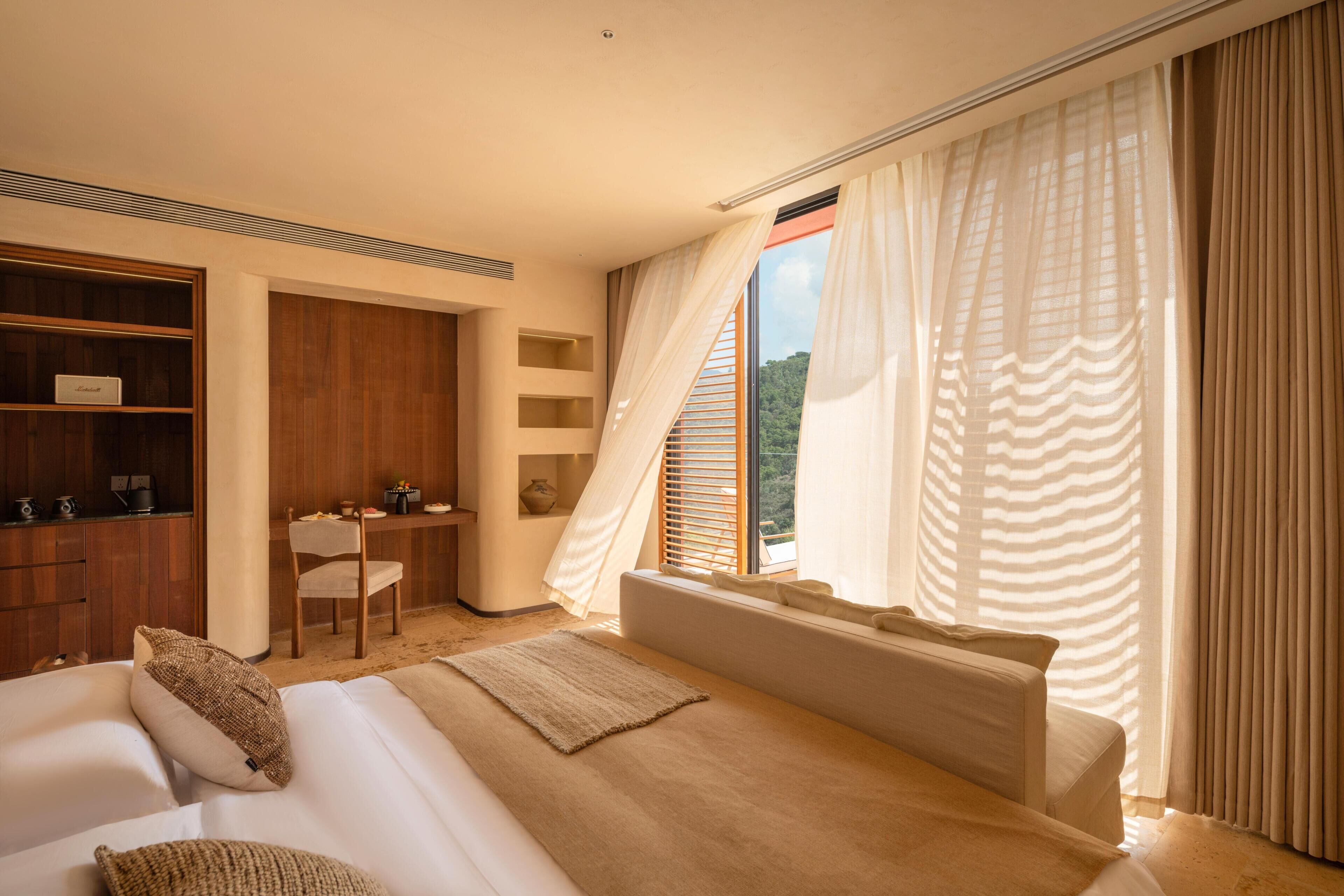 Une chambre avec un grand lit, un bureau et une vue sur l’extérieur.