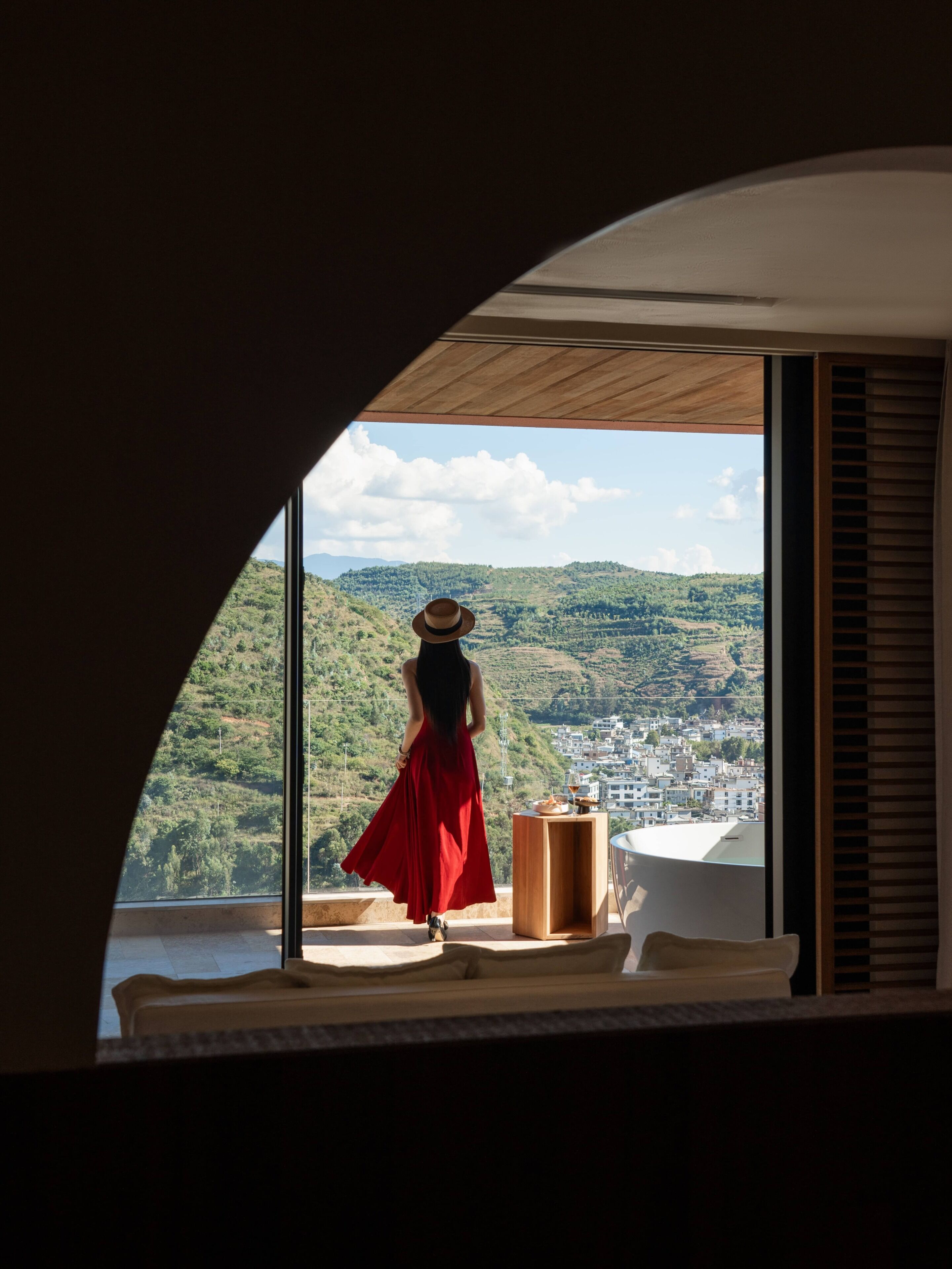 A room with a large arched window overlooking a landscape.