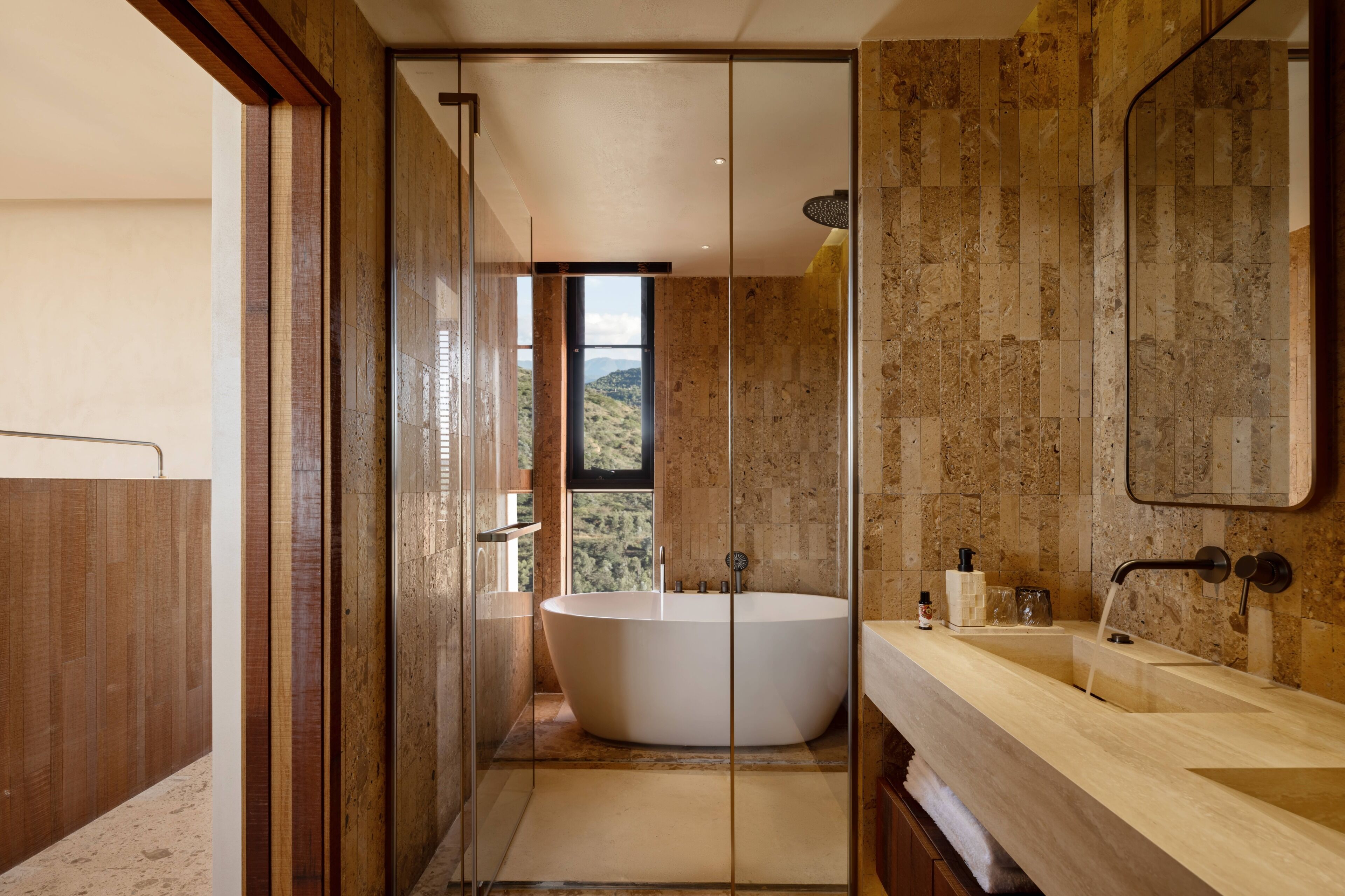 A modern bathroom with a freestanding bathtub, a large mirror, and a view of the outdoors.