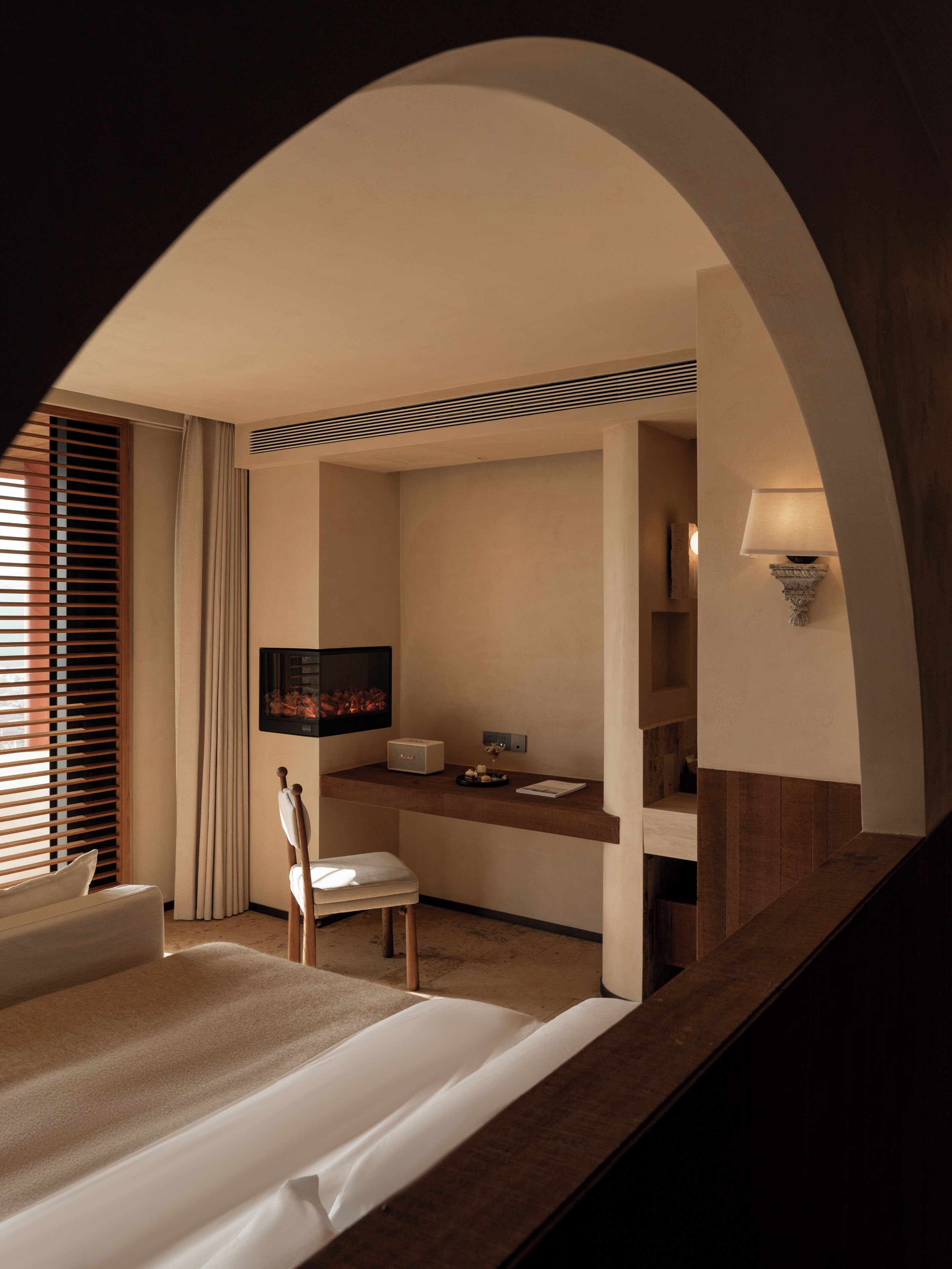 Een hotelkamer met een bed, bureau, stoel, televisie en lamp.