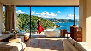 Une chambre d’hôtel moderne dotée d’une grande fenêtre en verre, d’une baignoire, d’un canapé et d’un coin repas.
