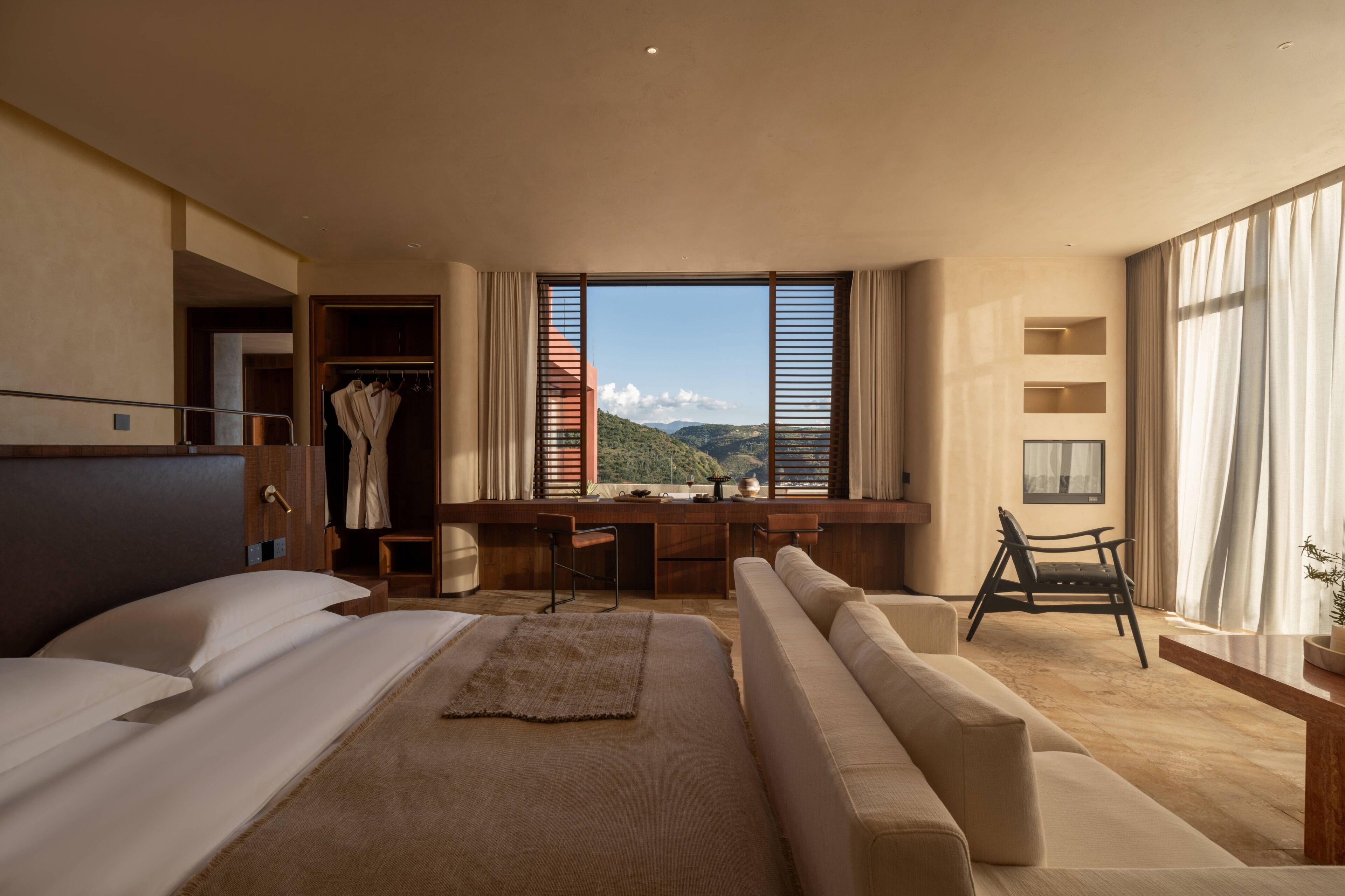 Una camera d'albergo con un letto grande, una scrivania, un divano e vista sulle montagne.