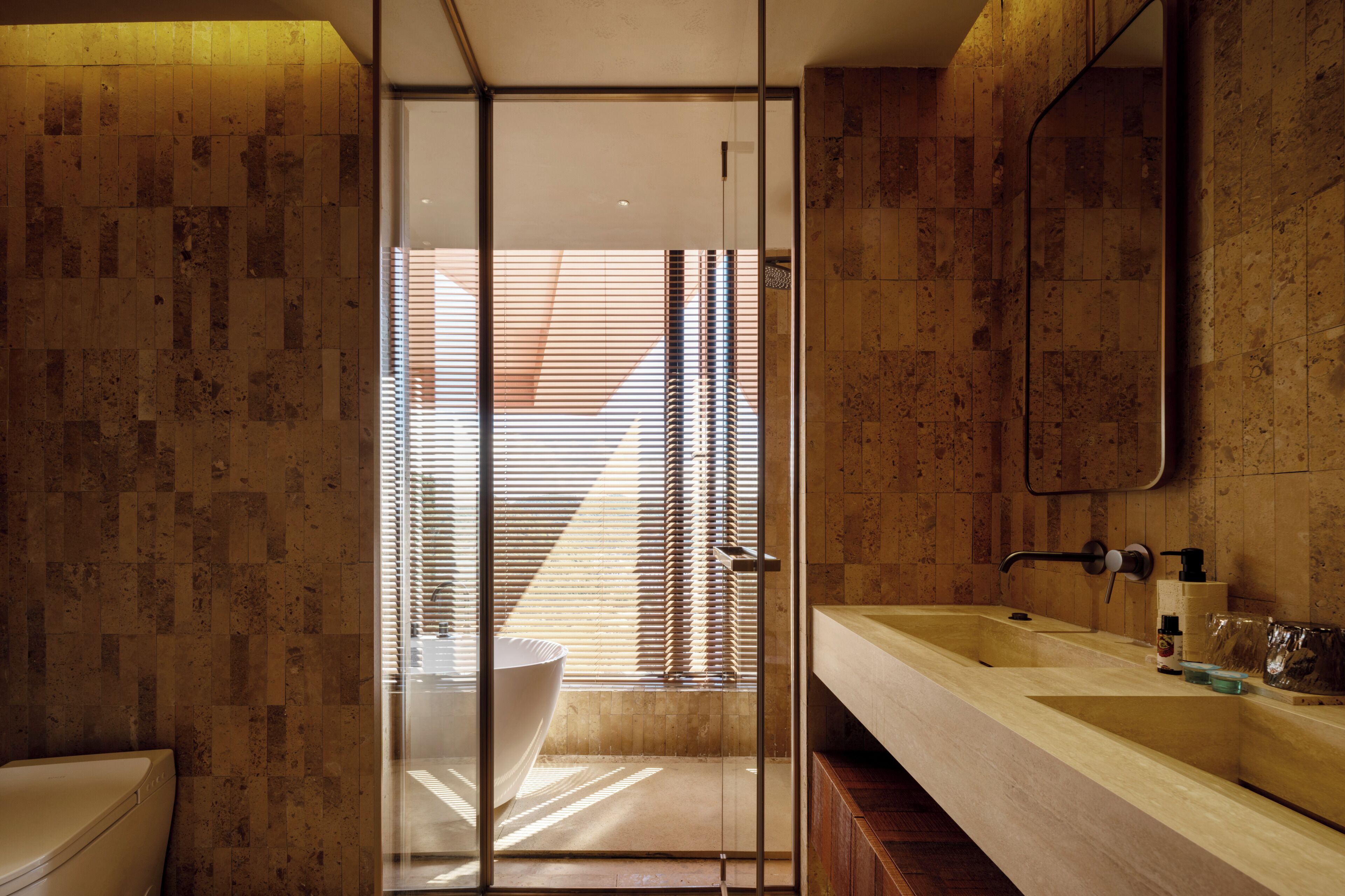 A modern bathroom with a large sink, a glass shower enclosure, and a wooden floor.