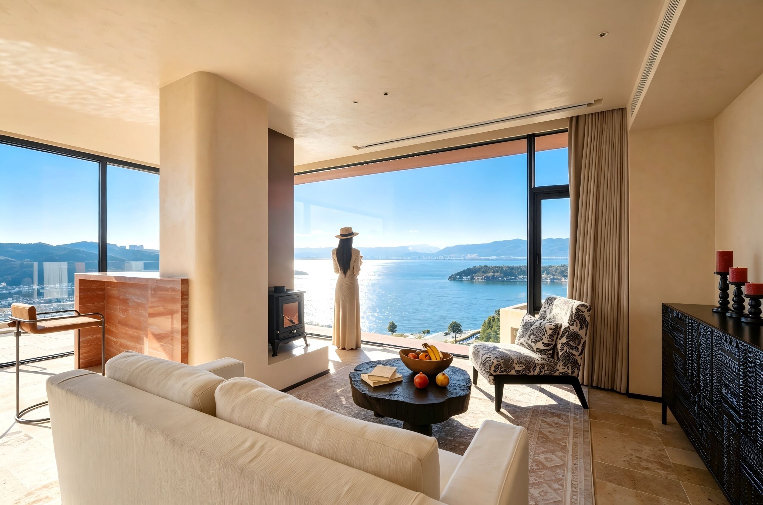 Un salón espacioso con un amplio ventanal que ofrece vistas al mar y a las montañas, una chimenea y muebles modernos.
