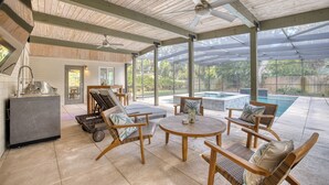 Un patio couvert avec des meubles en bois, une piscine et un coin bar.