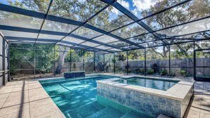 Une piscine extérieure couverte offrant une vue dégagée sur les arbres environnants et entourée d’une clôture en bois.