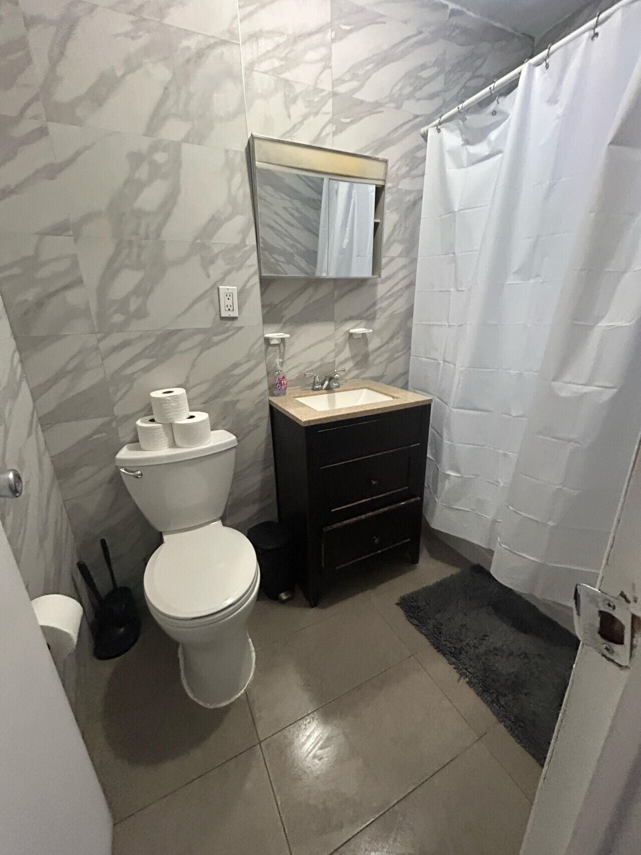 Een badkamer met toilet, wastafel en spiegel.