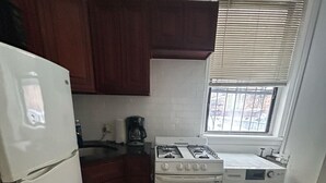 A compact kitchen with a refrigerator, stove, and washing machine.