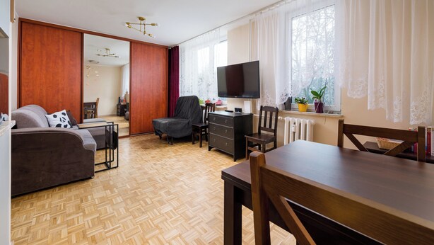 Ein modernes Wohnzimmer mit einer Couch, einem Esstisch und einem Fernseher.