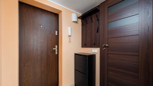 Ein Korridor mit zwei Holztüren, einem kleinen schwarzen Schrank und einem an der Wand befestigten Telefon.