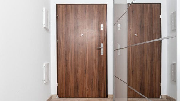 A hallway with two wooden doors, one with a sliding glass panel, and a light-colored floor.