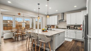 Uma cozinha espaçosa com uma ilha grande, armários brancos e luminárias pendentes modernas.