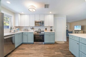 Una cocina moderna con gabinetes blancos, electrodomésticos de acero inoxidable y piso de madera.