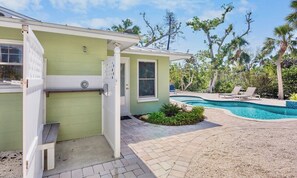 Une maison avec une piscine, un patio couvert et un petit jardin.