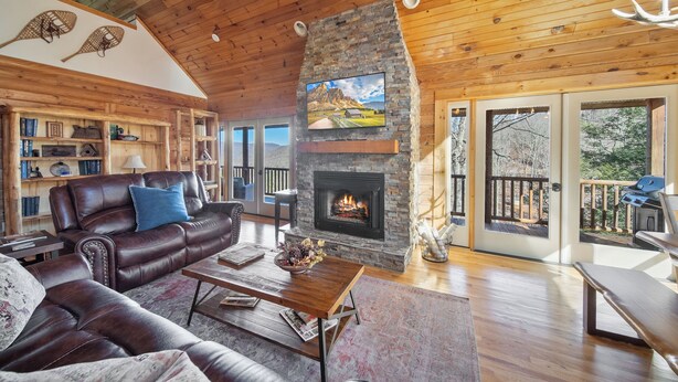 Ein gemütliches Wohnzimmer mit Kamin aus Stein, Ledersofas und Holzboden.
