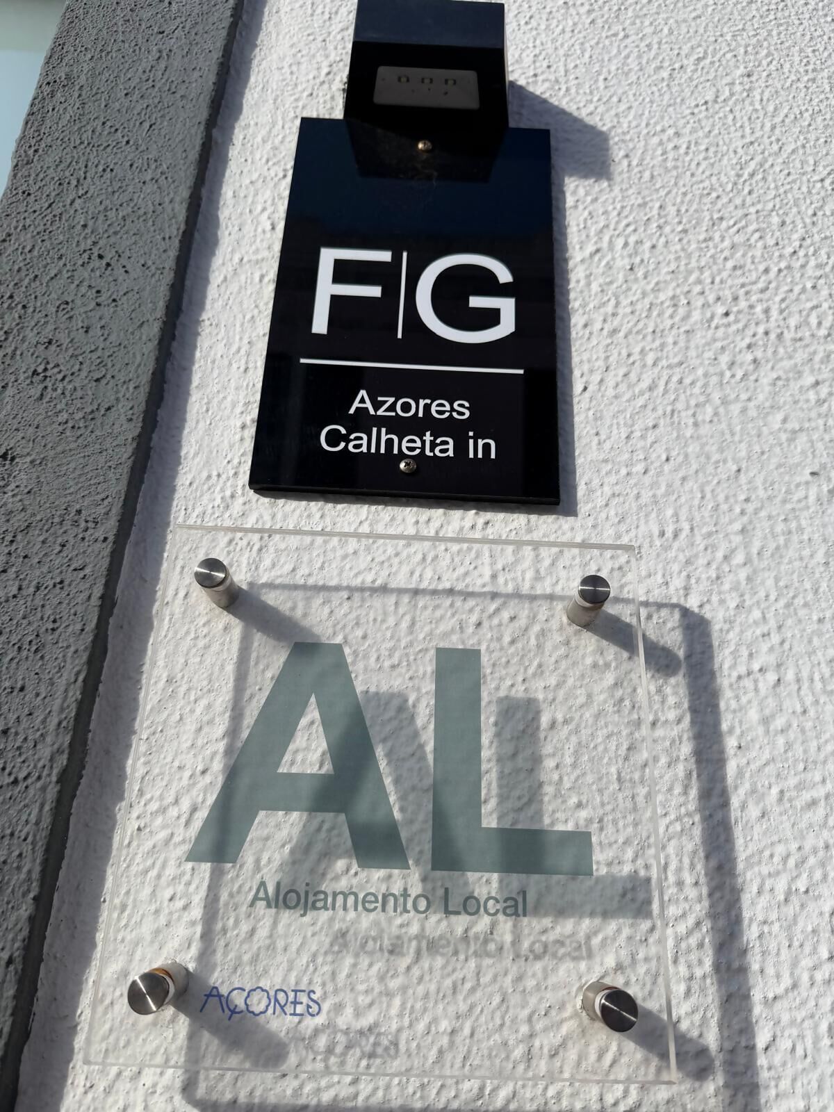 A sign with 'FIG' and 'Azores Calheta in' indicating a location. Below, a sign reads 'AL Alojamento Local' with 'Acores' written underneath.