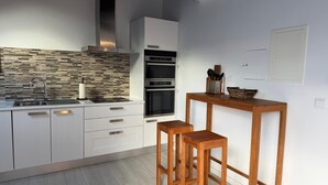 Una cocina moderna con armarios blancos, protector contra salpicaduras de piedra y un taburete de bar de madera.