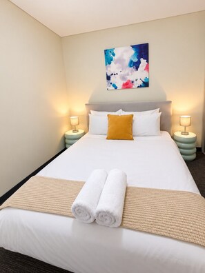 A hotel room with a bed, two bedside lamps, a painting on the wall, and a pair of towels on the bed. - Koala Cove on Rundle-Effortless Adelaide City Stay (Adelaide)