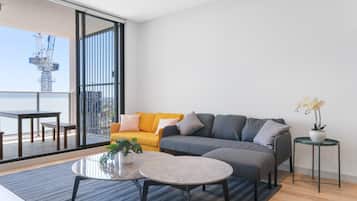 A modern living room with a sofa, coffee table, and a balcony with a view of a construction site.