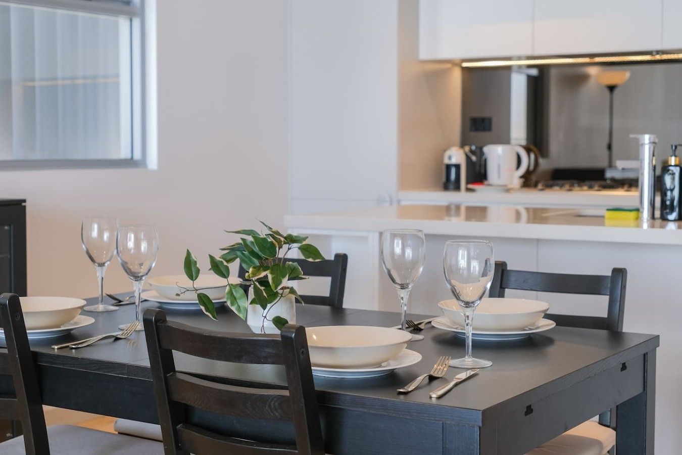 Een moderne eetruimte met een tafel voor zes personen, compleet met wijnglazen en borden, in een eigentijdse keuken.
