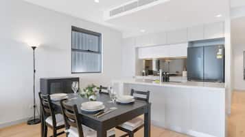 A modern kitchen with white cabinetry, a built-in oven, and a dining area with a table set for four.
