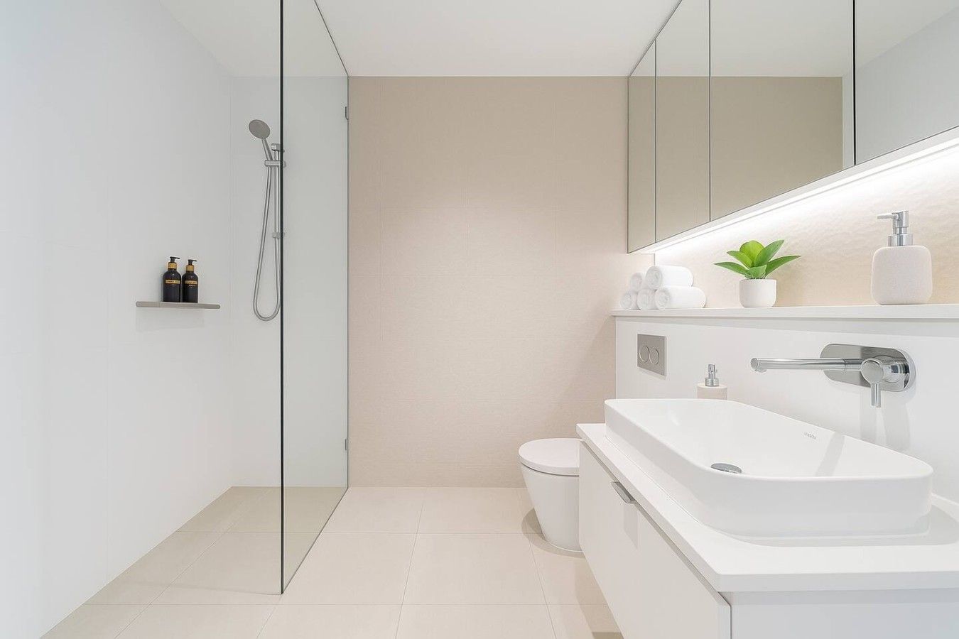 A modern bathroom with a glass shower enclosure, a white sink, and a toilet.