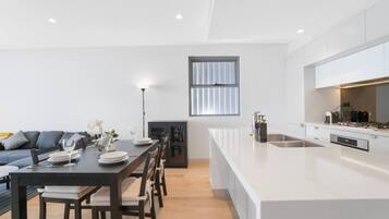 Une cuisine moderne avec un îlot central, un coin repas doté d’une table sombre et un canapé.