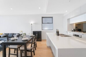 Een moderne keuken met een centraal eiland, een eetgedeelte met een donkere tafel en een bank.