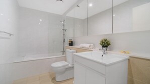 A modern bathroom with a glass-enclosed shower, a white toilet, and a vanity with a sink.