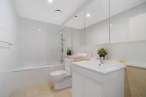 Un baño moderno con cabina de ducha de vidrio, inodoro blanco y tocador con lavabo.