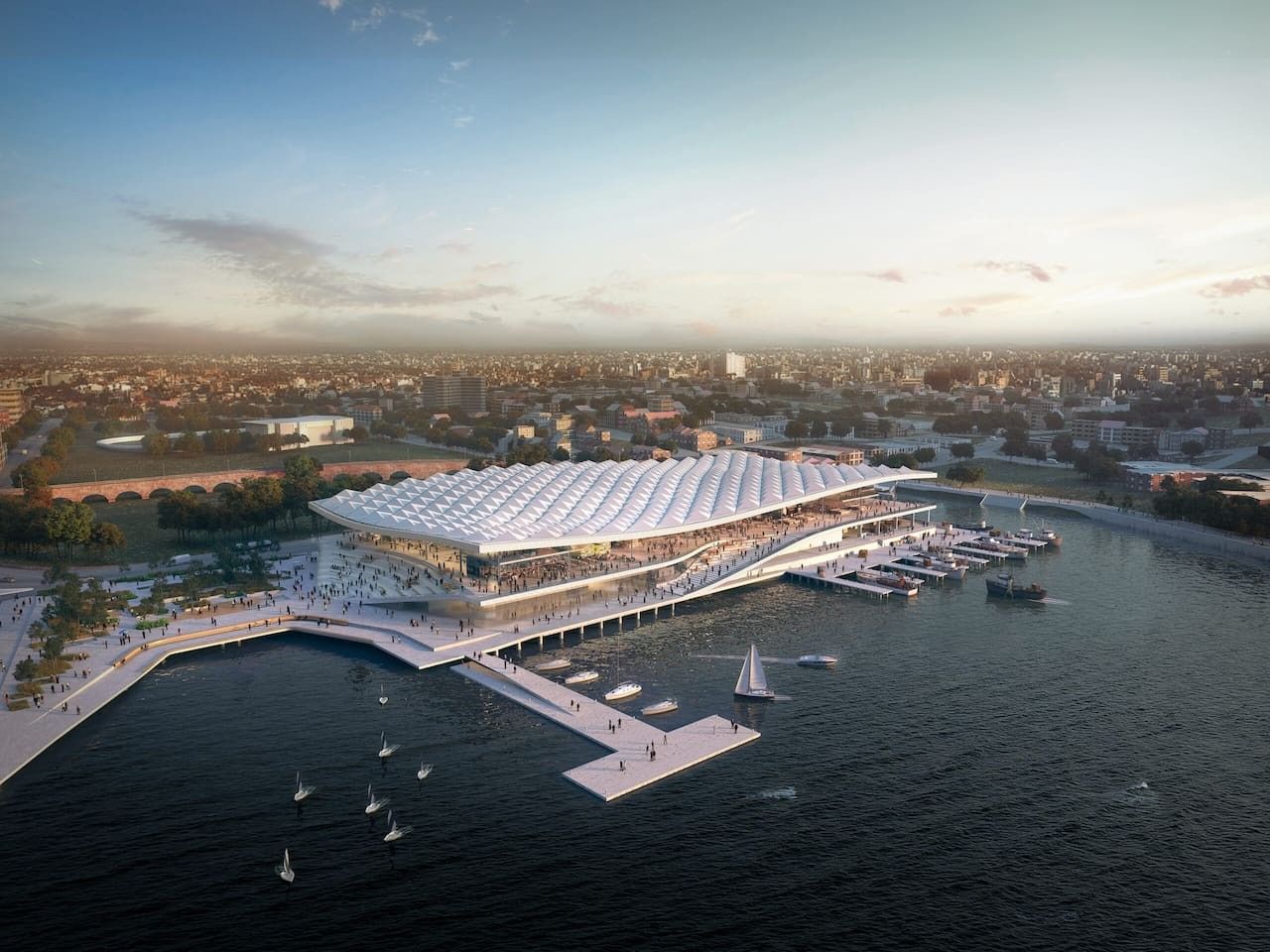 A waterfront building with a large, curved roof, connected to a dock with boats.