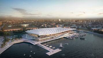 A waterfront building with a large, curved roof, connected to a dock with boats.