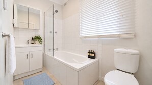 Een moderne badkamer met een bad, toilet en douche.