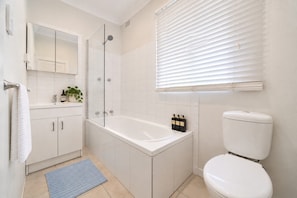 Et moderne badeværelse med badekar, toilet og bruseniche.