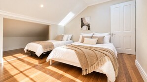 Een slaapkamer met twee bedden, een dakraam en een deur.