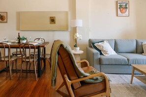 A cozy living room with a dining area, a sofa, and a table set for a meal. - New York Inspired Apartment w/ Sweeping City Views (Redfern)