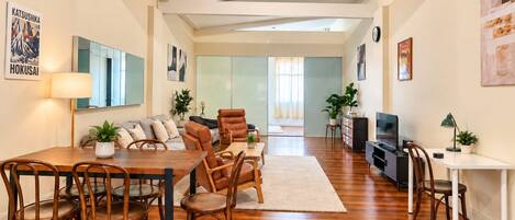 A modern living room with a dining area, a sofa set, a coffee table, and a TV.