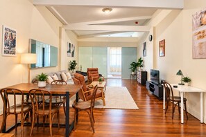 Un salon moderne comprenant un coin repas, un ensemble de canapés, une table basse et un téléviseur.
