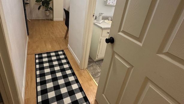 Um corredor com tapete quadriculado que leva a um banheiro.