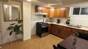 Cozinha compacta com armários de madeira, fogão e área de refeições com mesa e cadeiras.