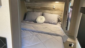 Ein kleines Schlafzimmer mit Bett, Kissen und einem Holzkopfstück.